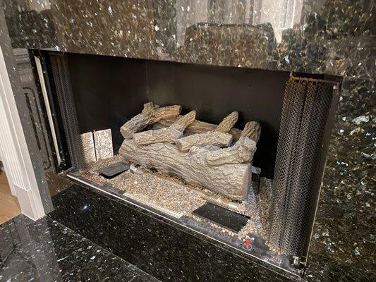 Fireplace with broken glass pieces that can be seen if looking at stones carefully