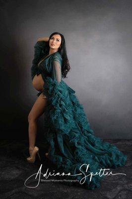 Maternity photo with beautiful mama wearing an emerald green couture robe standing in front of a charcoal backdrop