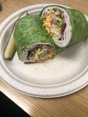 Turkey Bacon Club Wrap with spinach wrap and a fresh pickle.