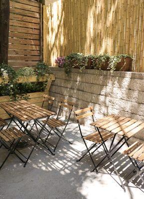 Tables in the lush backyard provide a relaxing spot to enjoy a cup of coffee or tea while you wait for your haircare services.