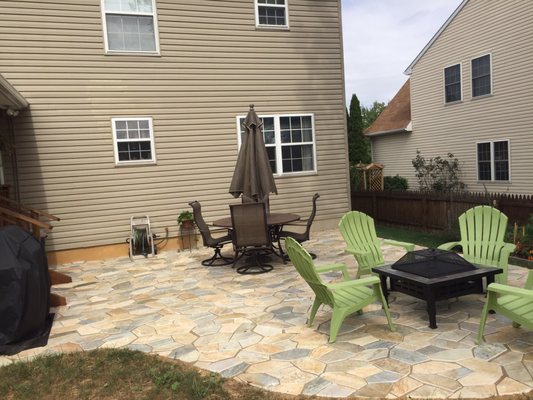 Stone patio installed to the side of porch addition