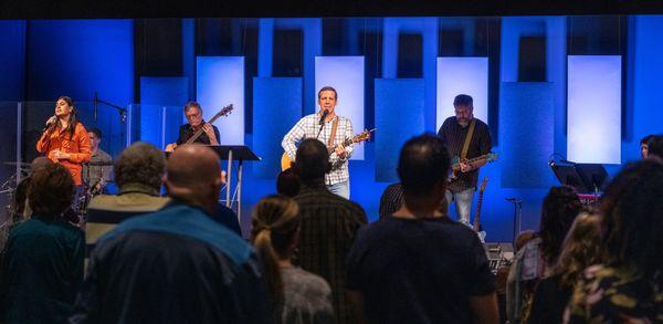 Worship leader, singing a song with the congregation in the foreground.