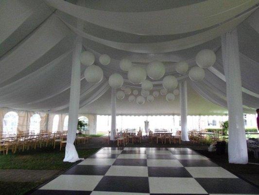 Black and white dance floor with ceiling drapery and globe lanterns.