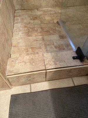 Before. Notice grout lines around base of shower and buckling curb tiles.