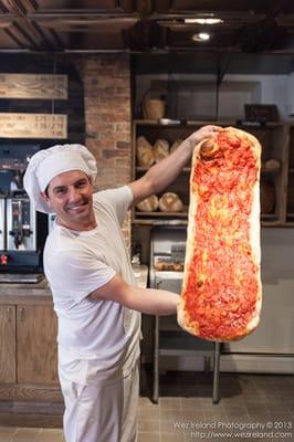 Massimo Ranni, owner of Massimo's Breads holds up one of the morning's first savory pies out of the kiln. Photo by Wez Ireland.