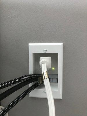 Recessed outlet in drywall for mounted TV. Shown: a power cord and  three HDMI cables leading to TV.