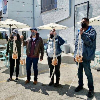 outdoor macrame plant hanger workshop - group of four holding their finished macrame pieces and terracotta planters!