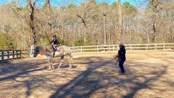 Instructor Meredith Philipps teaching a lunge lesson to a regular student on lesson horse Paco.