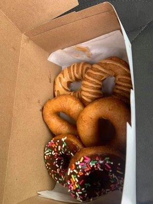 Two donuts with chocolate icing and sprinkles, two plain and two with peanut butter sauce!