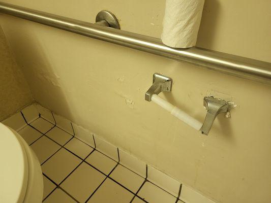 Toliet paper holder damaged and not functional.  Walls are in need of repairs.