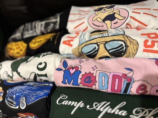 Assortment of screenprinted t-shirts, baby tees, oversized tees, and more. All projects completed at the Embroidery Shop.