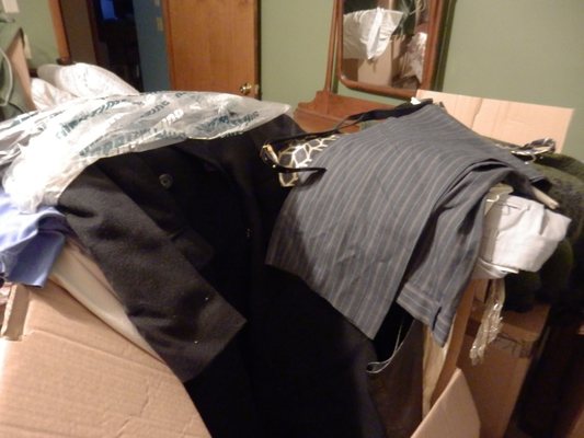 More suits, leathers, and dress clothes piled into another wardrobe box.