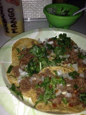 An order of tacos with onion and cilantro and red salsa.