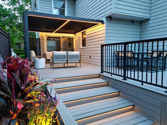 Close-up of contemporary deck in Bayside, highlighting LED step lighting and a vibrant flower bed, designed by Vandeck Builders.