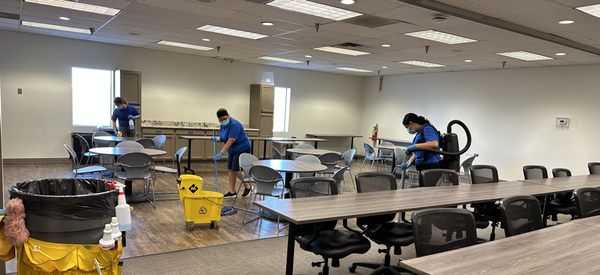 Colorado's best cleaners are diligently cleaning and disinfecting a spacious conference room to prepare it for the next day.