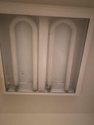 Bare fluorescent bulbs with no cover in kitchen light fixture.