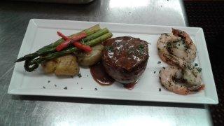 Steak medallion topped with demi glace. braised pesto prawns, smashed Yukon gold potatoes, grilled asparagus. garnished with parsley.