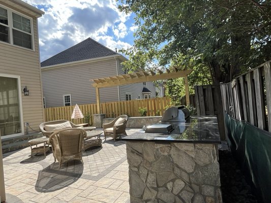 Island with built-in grill and cooktop. Paver patio. seating wall with trellis.