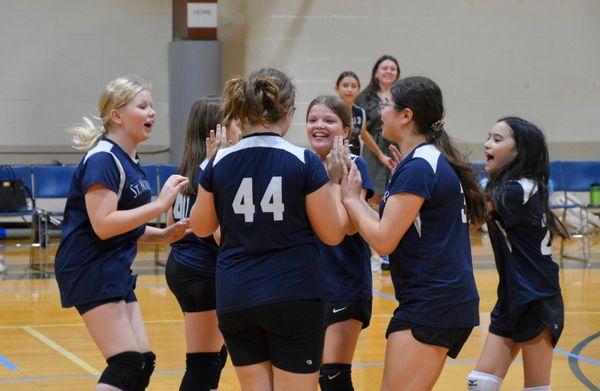 Girls volleyball team celebrates a win.