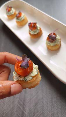 House artichoke and kale dip placed on a toasted brioche toast with roasted heirloom tomatoes. A great burst of flavor.