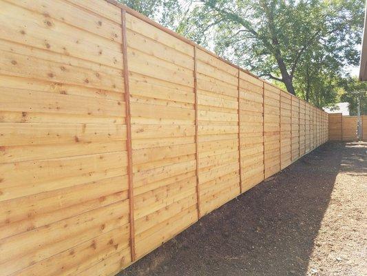 8' cedar horizontal fence with 2"x2" every 6'. 2"x6" cap top. Raw wood not stained. Designed and built by Green and Son. Dallas, Texas.