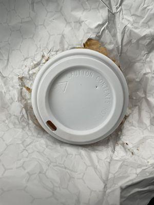 Burger under small coffee drink lid.