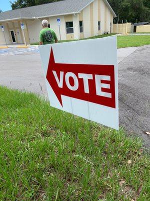 Husband following the sign to vote.