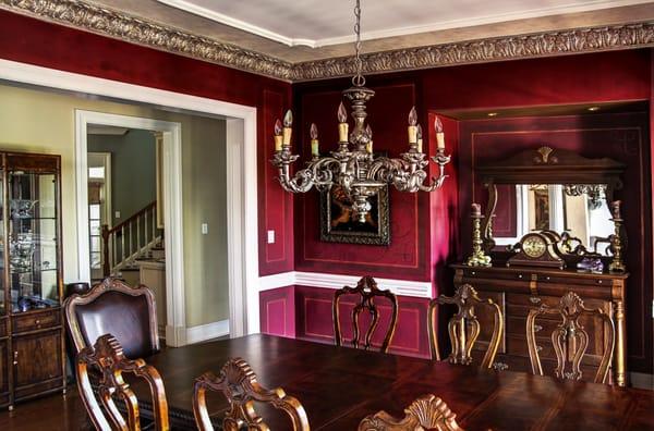 Stencil designs over wine colored walls with a faux metal plaster cornice and chandelier topped with an accented ceiling.