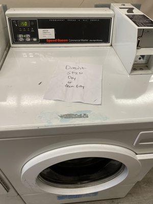 A washing machine with an out of order sign handwritten on top.