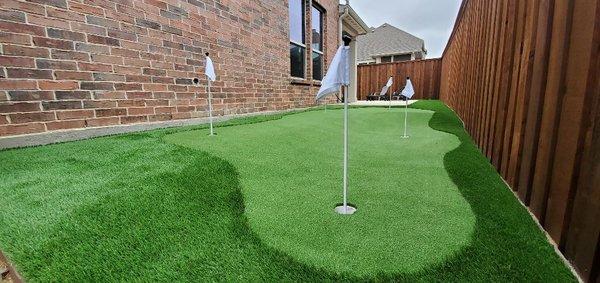 A five-hole, multi-level putting green in a residential side yard.