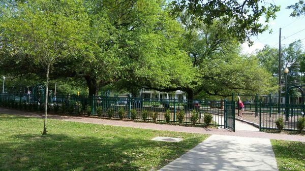 Fenced-in, smoke-free play area with benches and swings for sitting under the trees