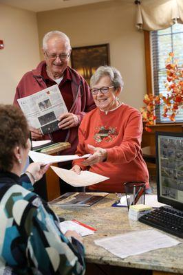 Two residents pick up their mail from the reception desk.