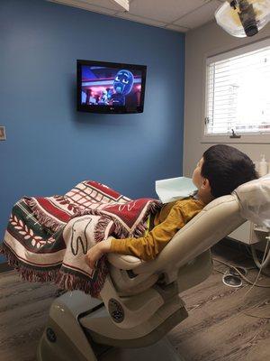 5 year old, snuggled in a blanket, watching PJ Masks in the dentist chair while waiting for the novocaine to kick in