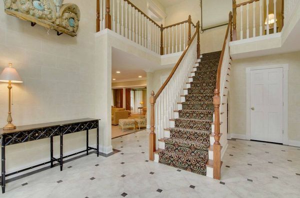 Custom built flared staircase with marble tile flooring, that is flanked by the sunken floor living room and dining room.