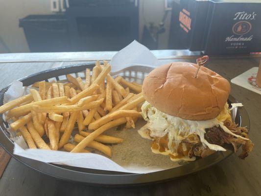 Pulled pork BBQ sandwich with fries .