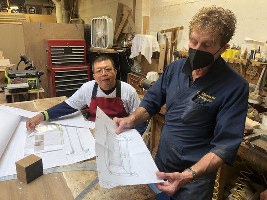 Claudio shows off a design for a hand carved piece.  Behind him is his master wood carver, Jesus.