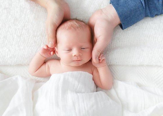 Baby girl holding her parent's hands.