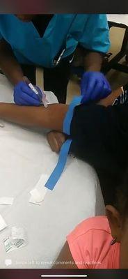 Blood being drawn from patient at her work desk.