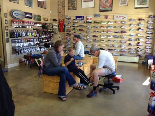 Michael fits a young customer with kids' shoes.