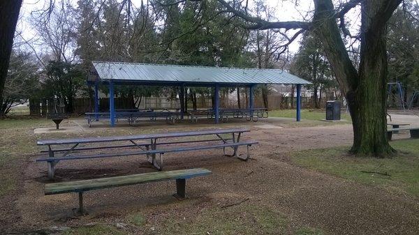 a shelter with picnic tables and a grill