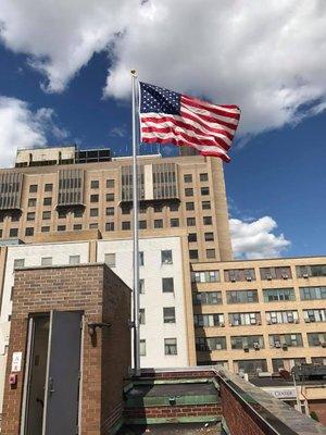 Wall mounted aluminum flagpole mounted on the roof of the building.