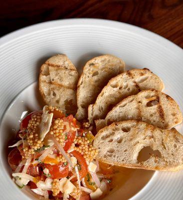 Panzanella, with cherry tomatoes and an herbed vinaigrette, garnished with pickled mustard seed