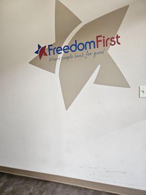 The artwork design of the logo of Freedom First Credit Union located on the wall at the right side as you enter the building.