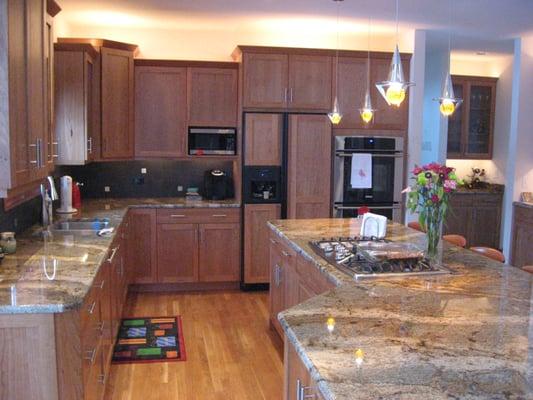 Contemporary kitchen with natural cherry cabinets, Lapidus granite, under cabinet lighting, & fun pendant lights