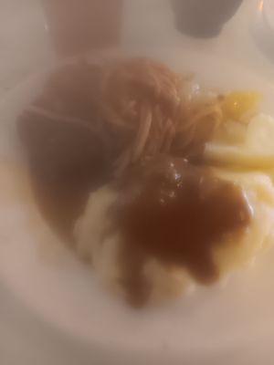 Close up of mashed potatoes and gravy with hamburger steaks and spaghetti etc