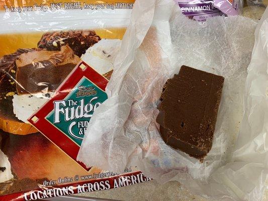 Slice of extraordinary chocolate (partially eaten) and iconic Fudgery bag.