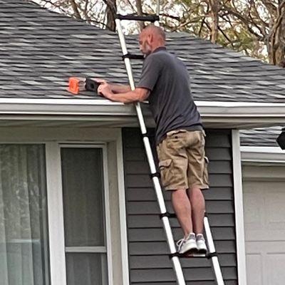 Sales Representative, Wes, inspecting a homeowners roof for storm damage.