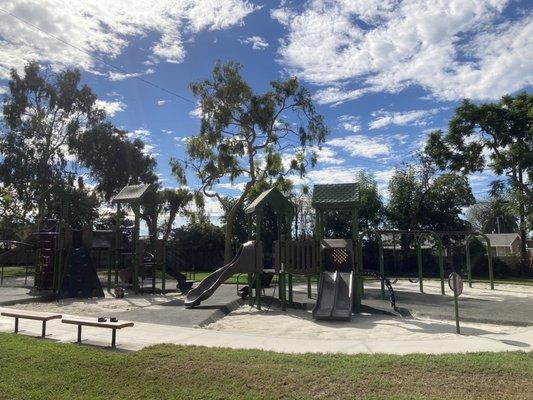 Playground with sand and rubber, multiple slides and swings.