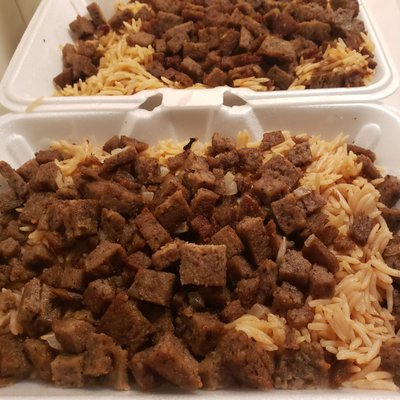 Lamb Over Rice.  White and red sauce and salad on the side.