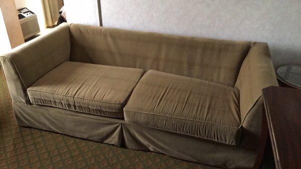 Couch that's been drug from the alley and put in room...equipped with stains and missing back cushions